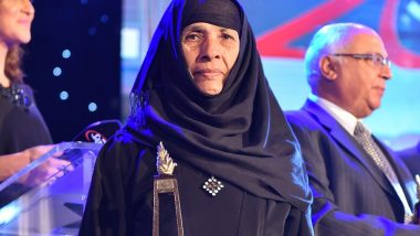 Widow in traditional black clothing holds her award