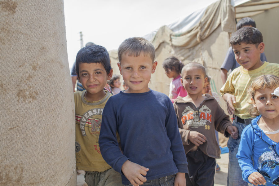 Young Syrian boys beside tents in a refugee camp