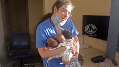 Female nurse holds three newborn babiesin her arms