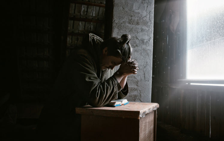 Woman praying in dark room