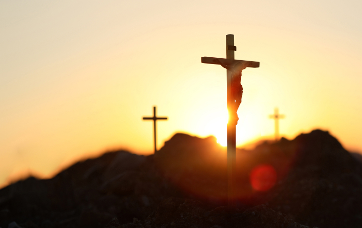 Three crosses on hill at sunrise