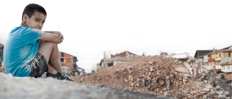 Boy with blue shirt sitting in rubble