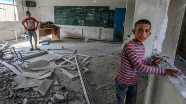Children stand in destroyed classroom