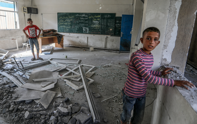Children stand in destroyed classroom